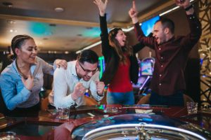 Cheerful group of friends enjoys winning poker roulette in a casino